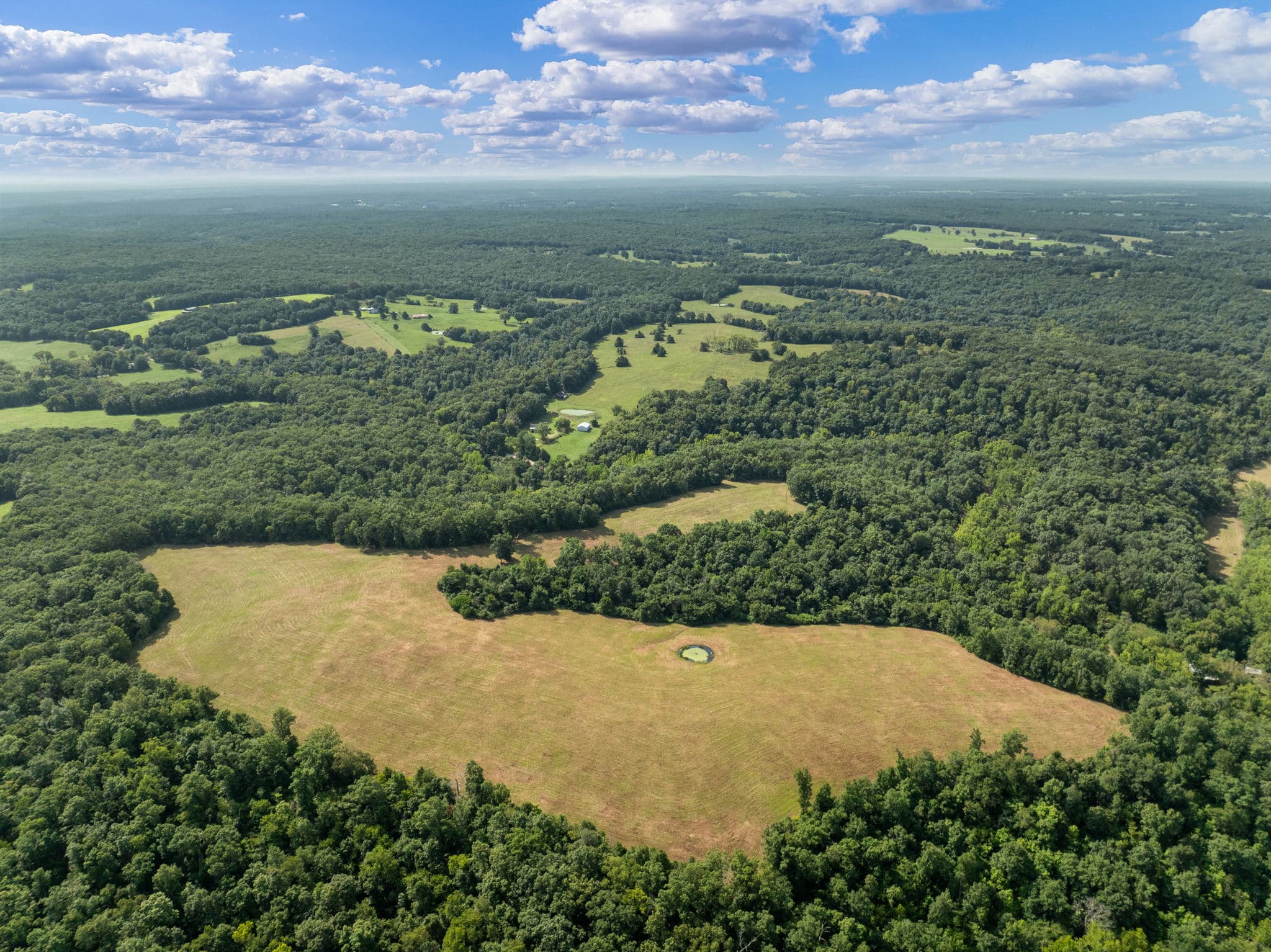 Aerial view of open pasture ringed by mature timber at Long Spring Ranch