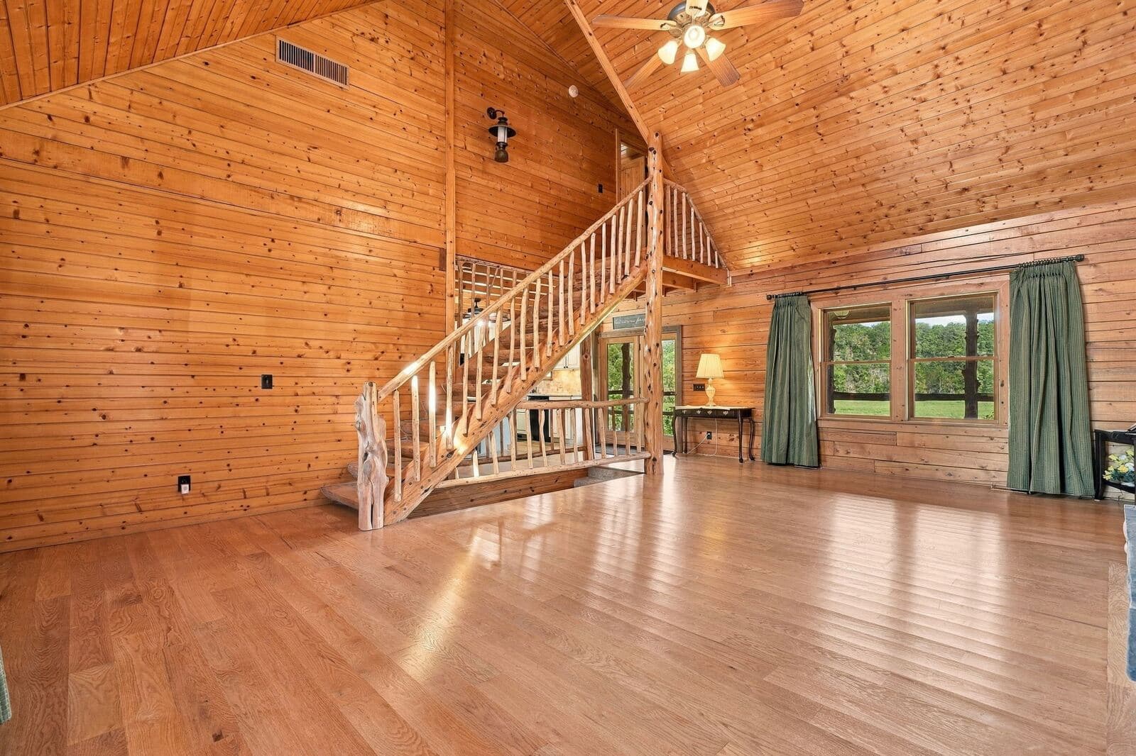 Great room with vaulted pine ceiling and log staircase