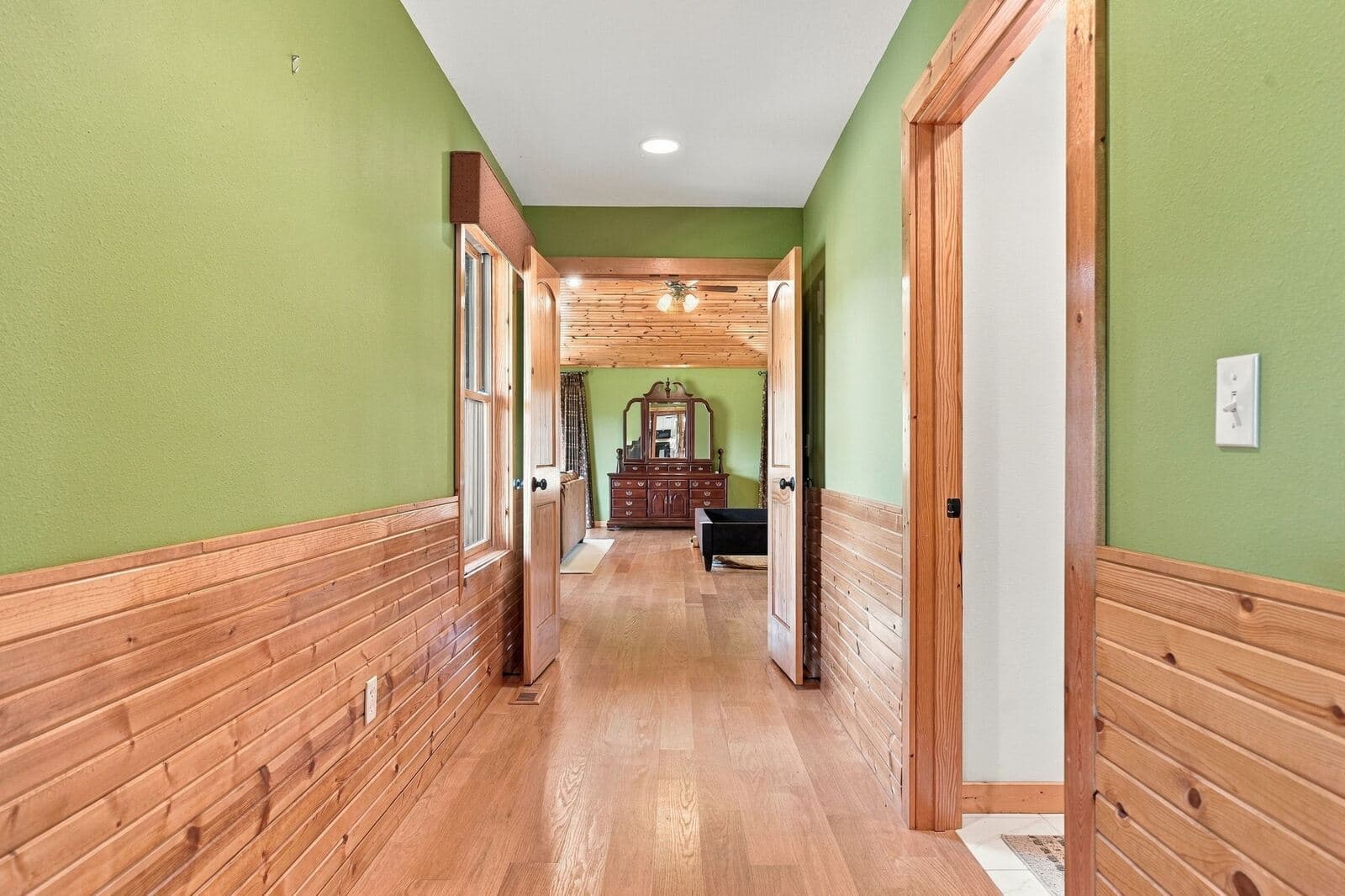 Hallway with hardwood floors and wainscoting