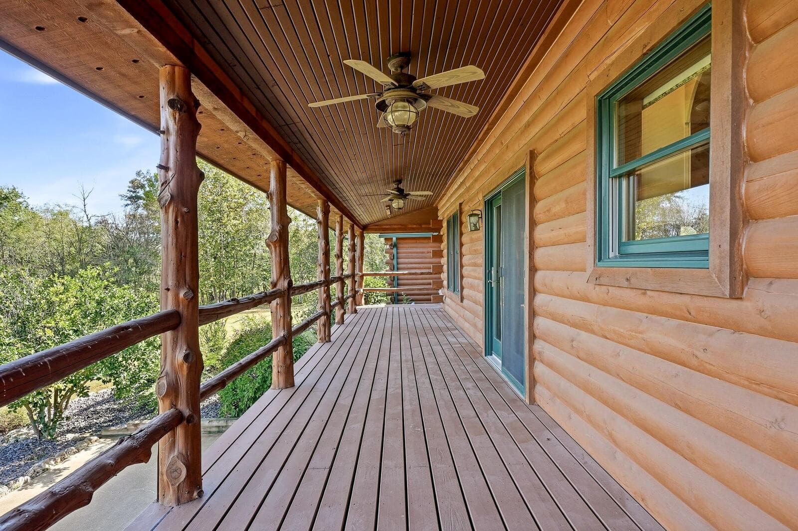 Covered porch with ceiling fans along the log home