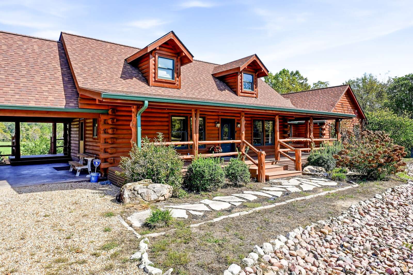 Log home exterior with stone walkway and covered porch