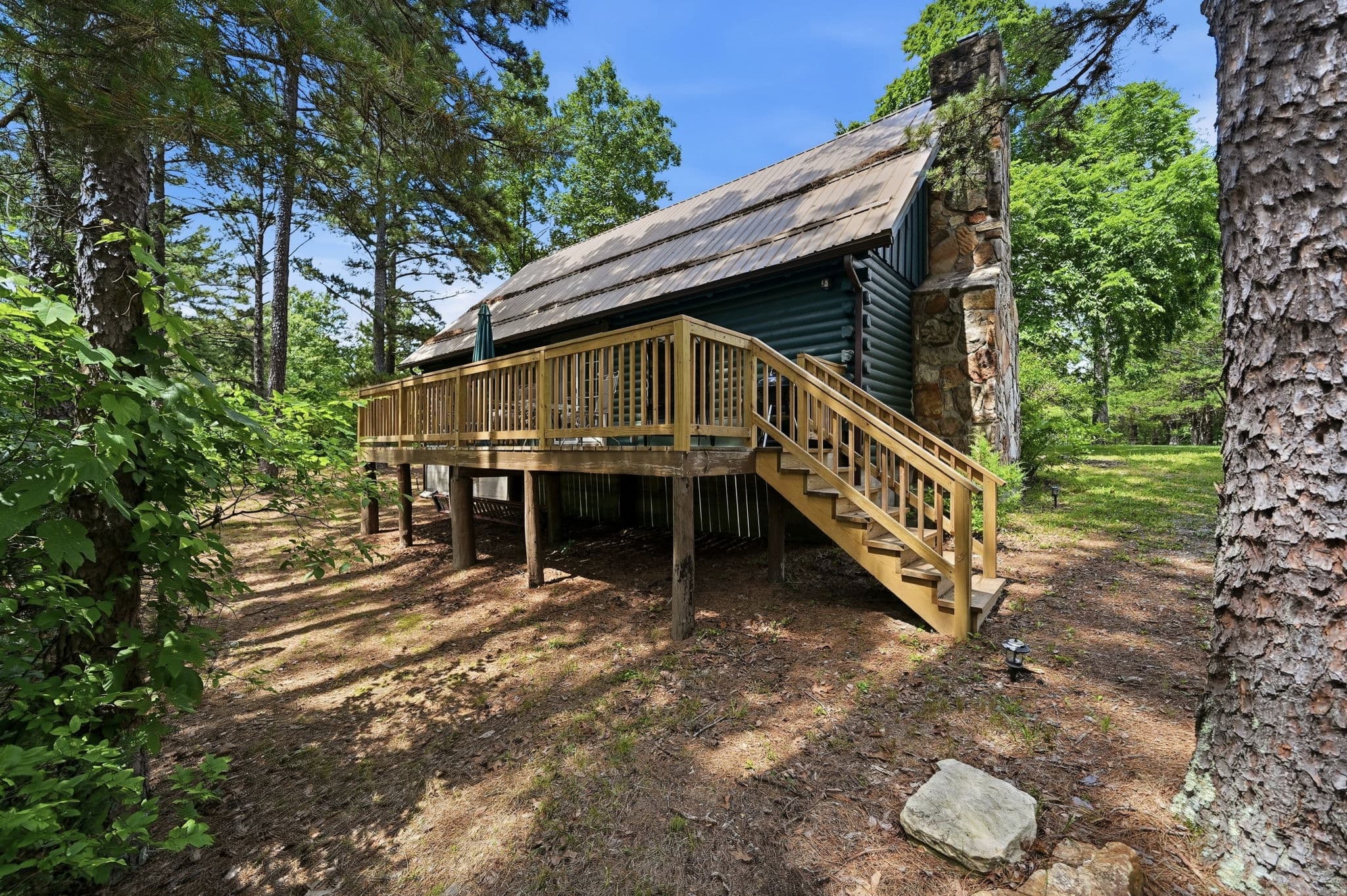 Elevated deck and stone chimney seen from the treeline
